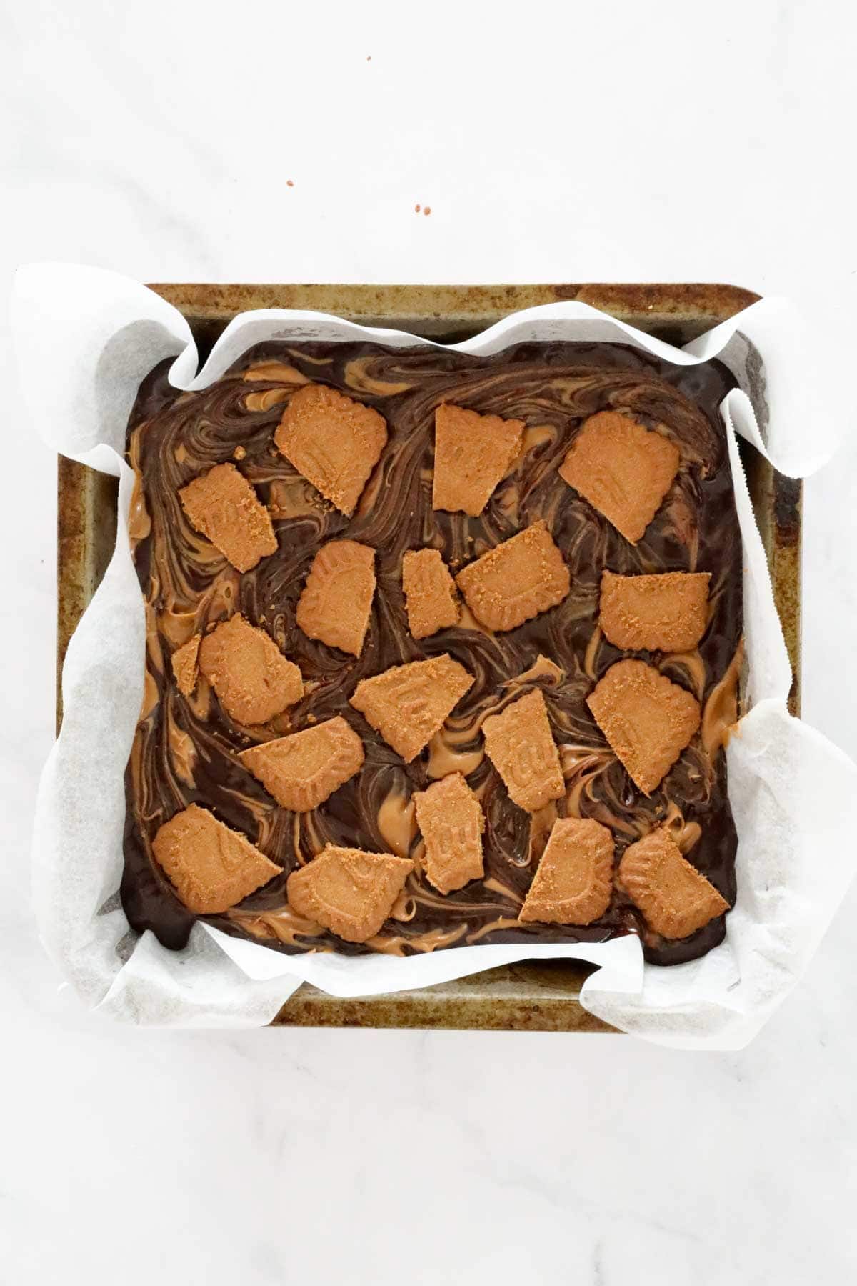 Chunks of Biscoff biscuit placed on top of slice before baking.