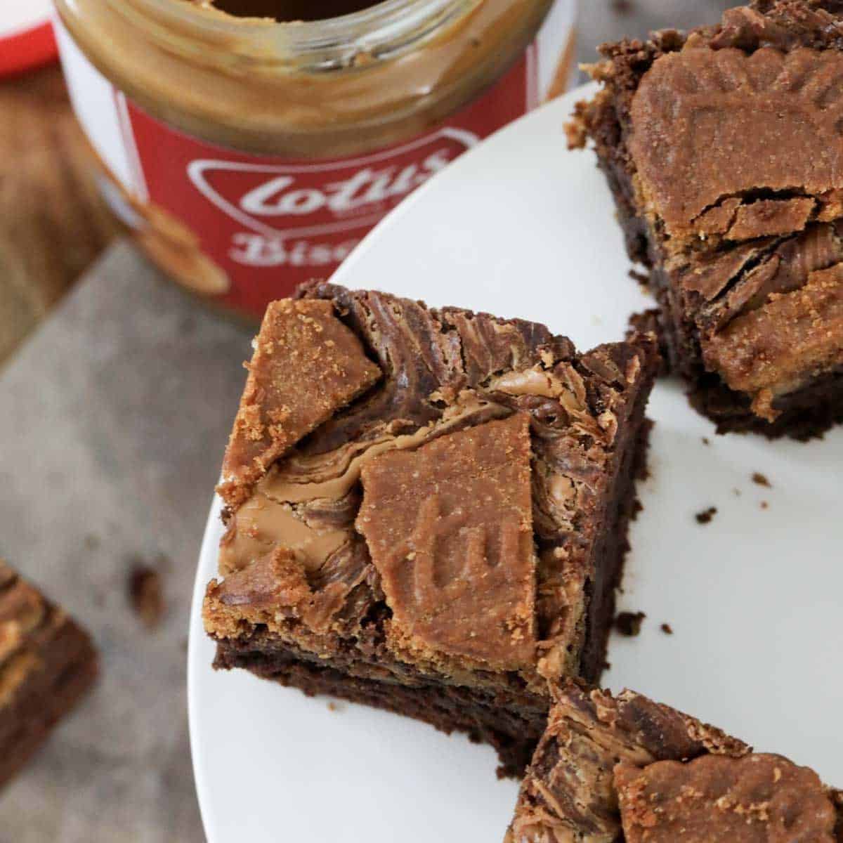 An overhead shot of a jar of Biscoff with pieces of chocolate brownie.