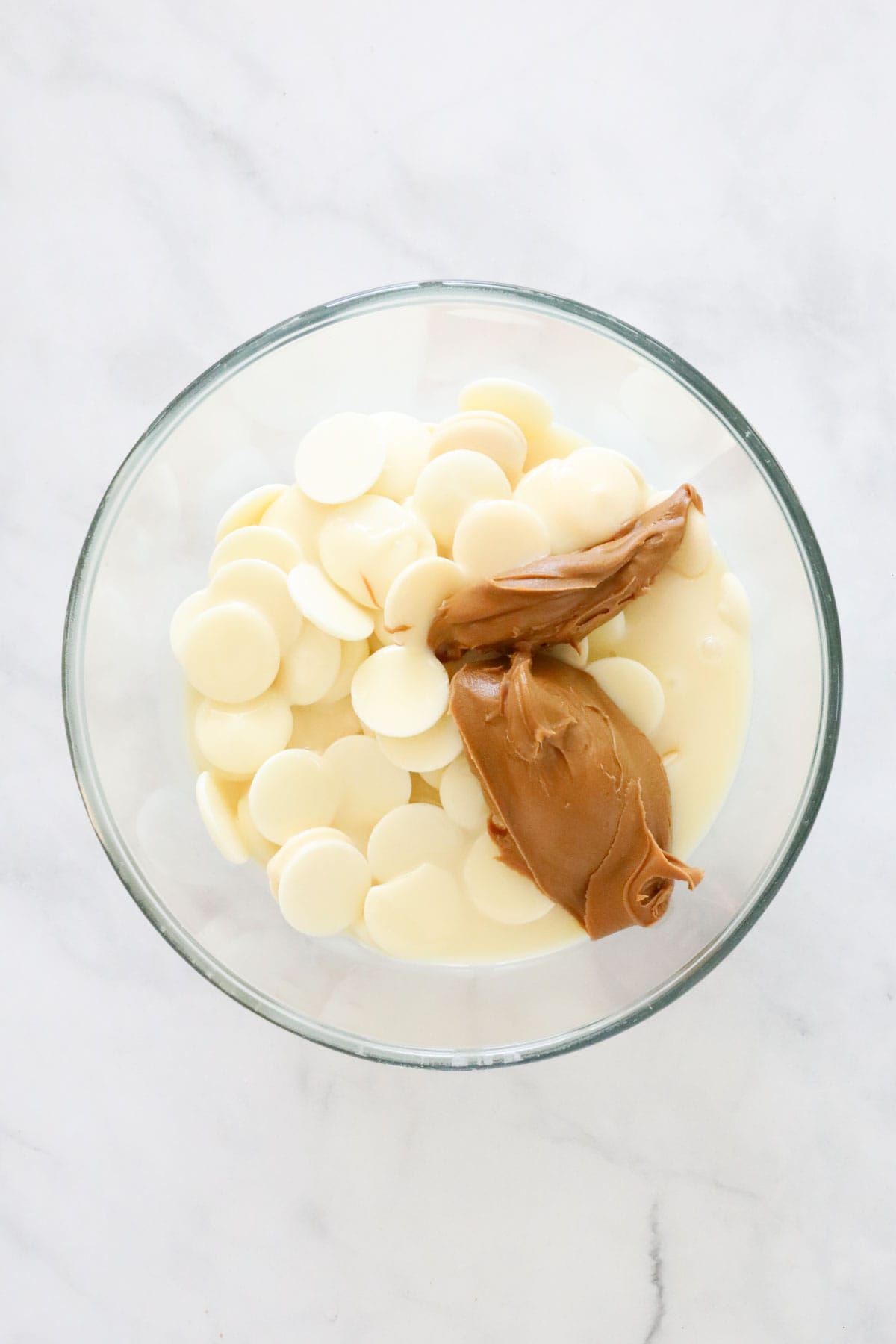 White chocolate melts, condensed milk and cookie butter in a mixing bowl.