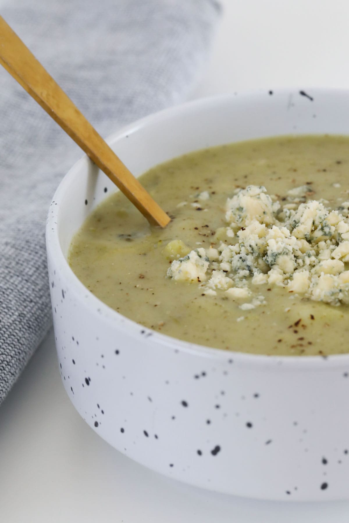 Broccoli and blue cheese soup in a bowl with a gold spoon.