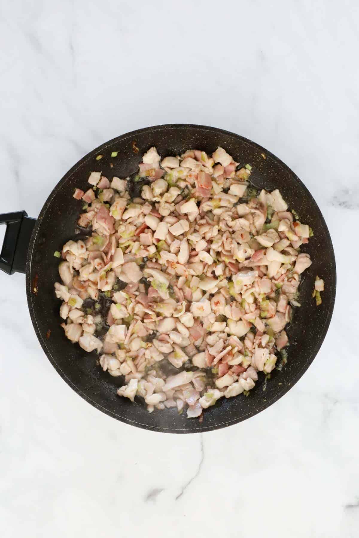 Chicken, leek and bacon cooking in a frying pan.
