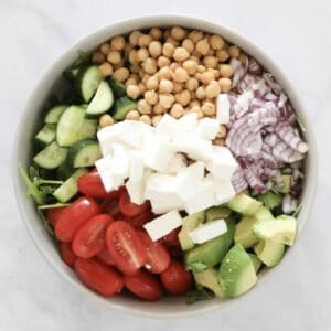 A bowl filled with salad vegetables, chickpeas and avocado.