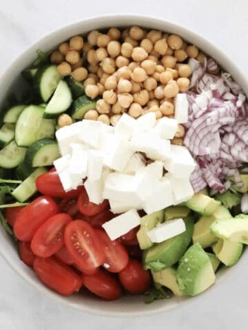 A bowl filled with salad vegetables, chickpeas and avocado.