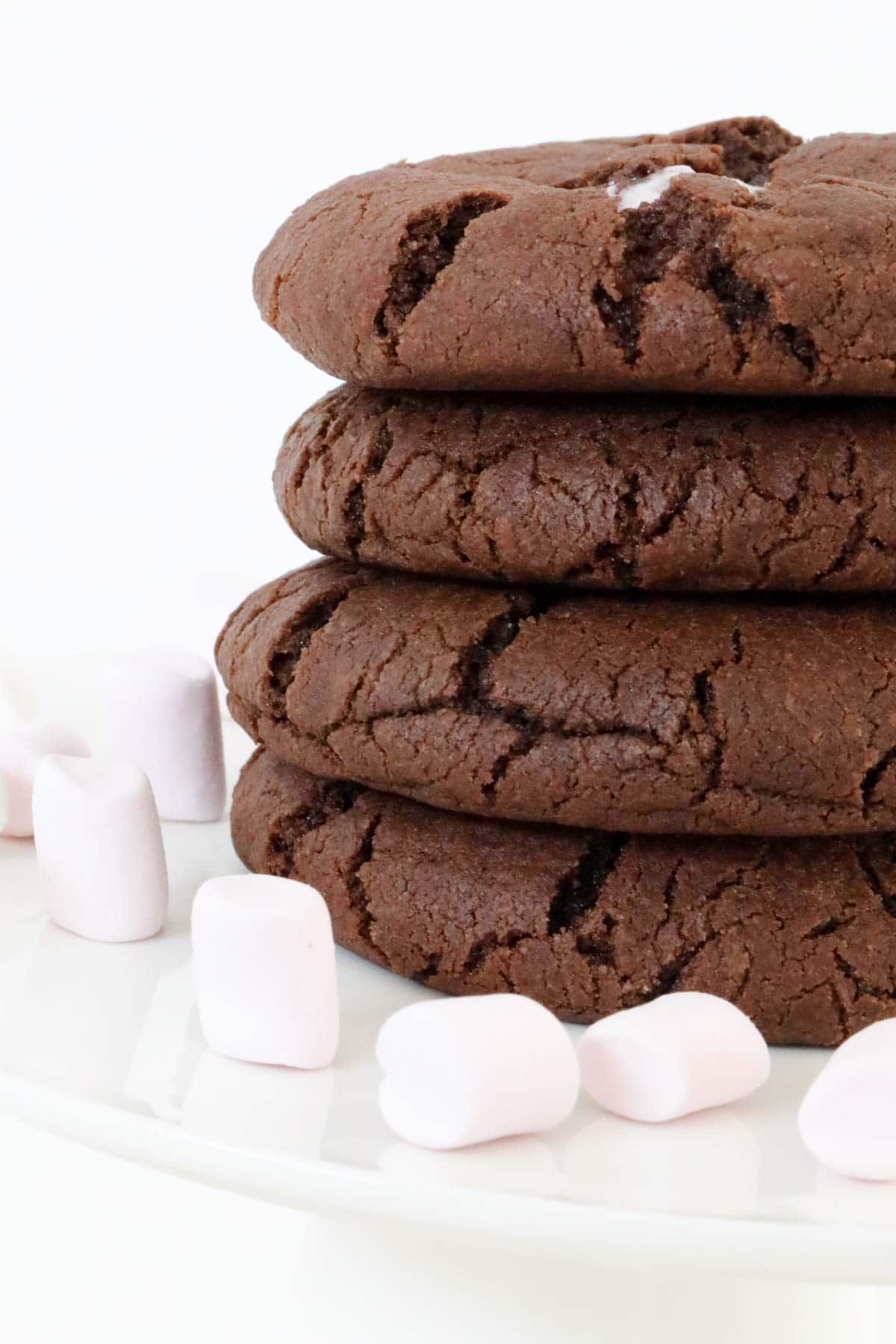 A pile of four chocolate cookies, surrounded by mini marshmallows.