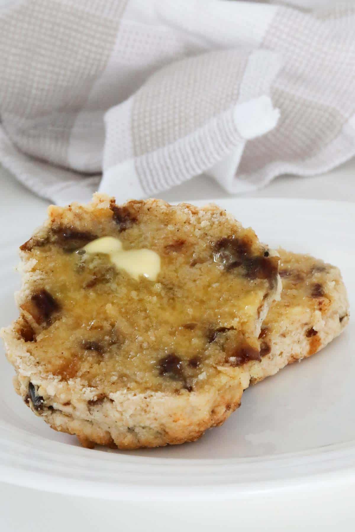 Melted butter on half a scone, served on a plate.