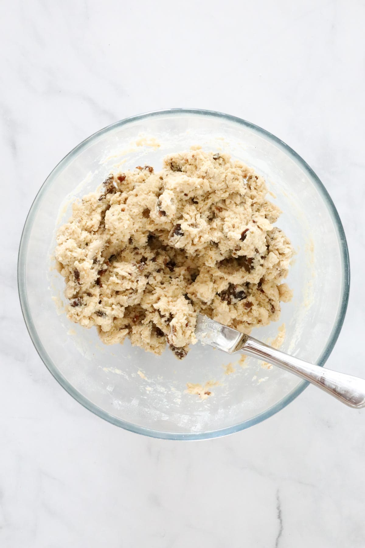 Dough mixture and a flat knife in a clear glass bowl.