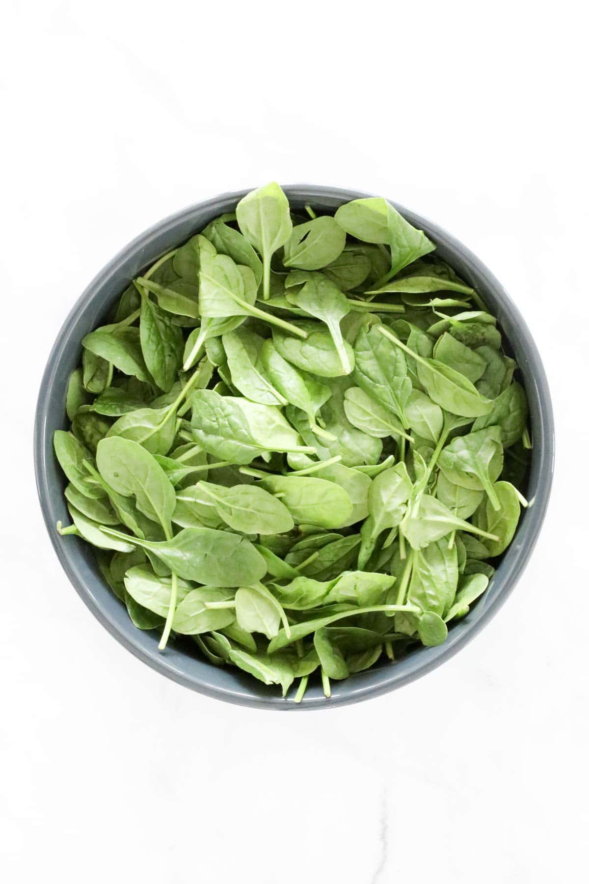 Baby spinach placed in a large serving bowl.