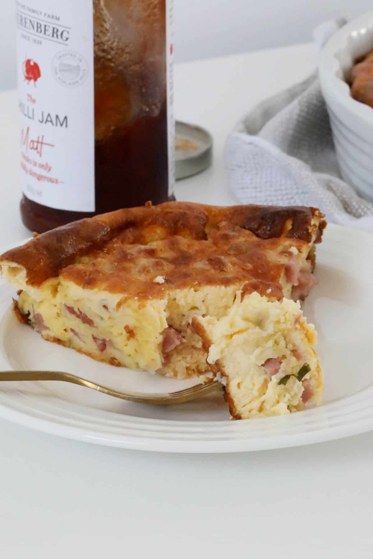 A serve of crustless quiche on a white plate with some on a fork.