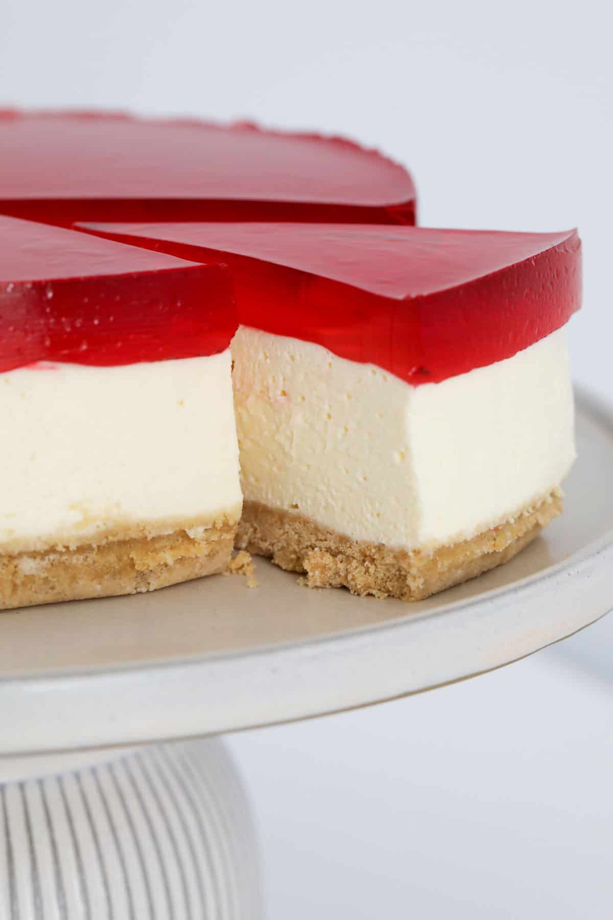 Side view of the jelly cheesecake with a slice taken out to show the layers of the cheesecake.