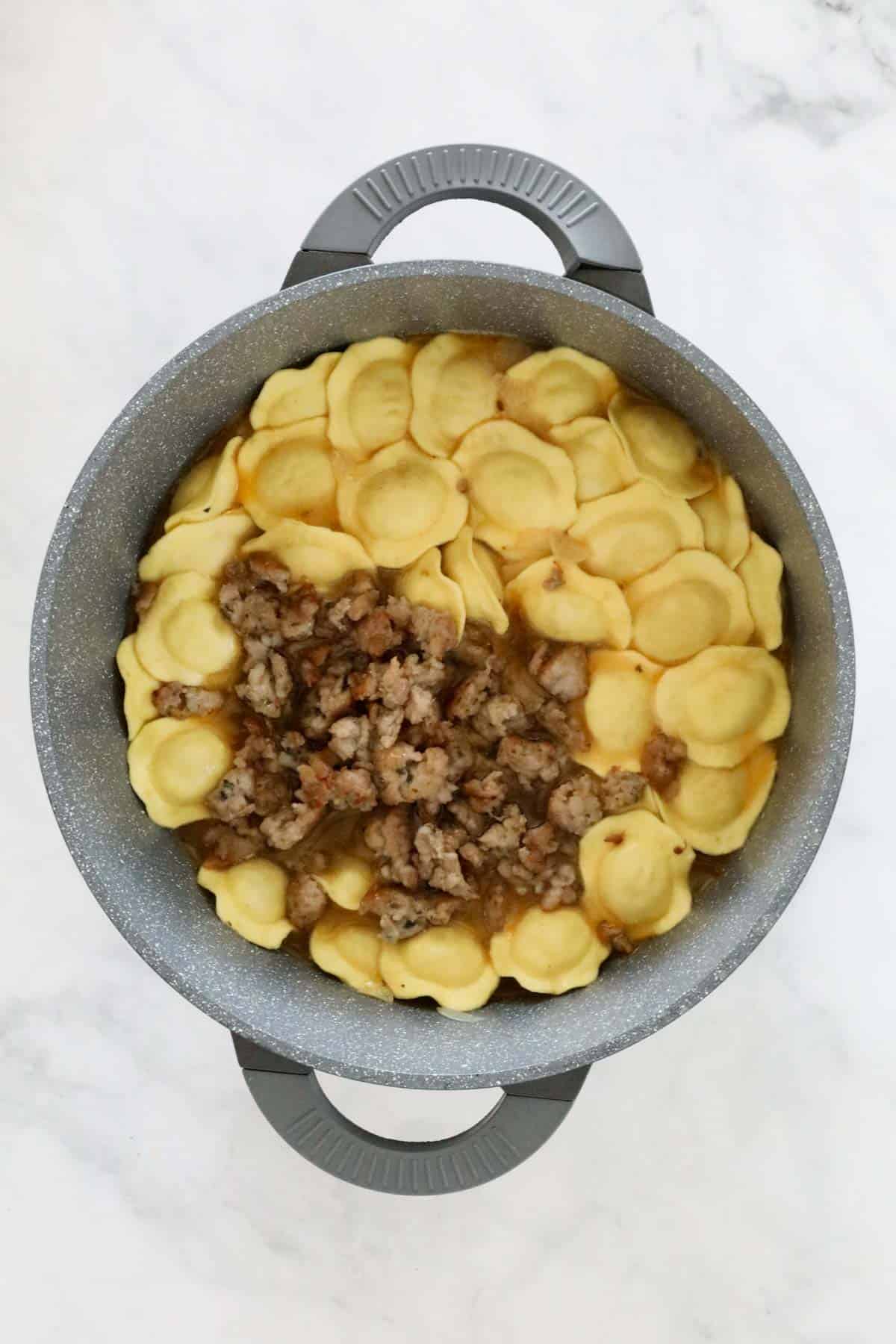 The cooked sausage and tortellini added to the pan.
