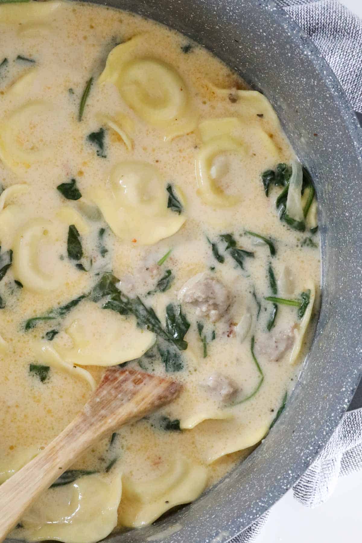 A pan of cooked creamy Tuscan tortellini sausage soup.
