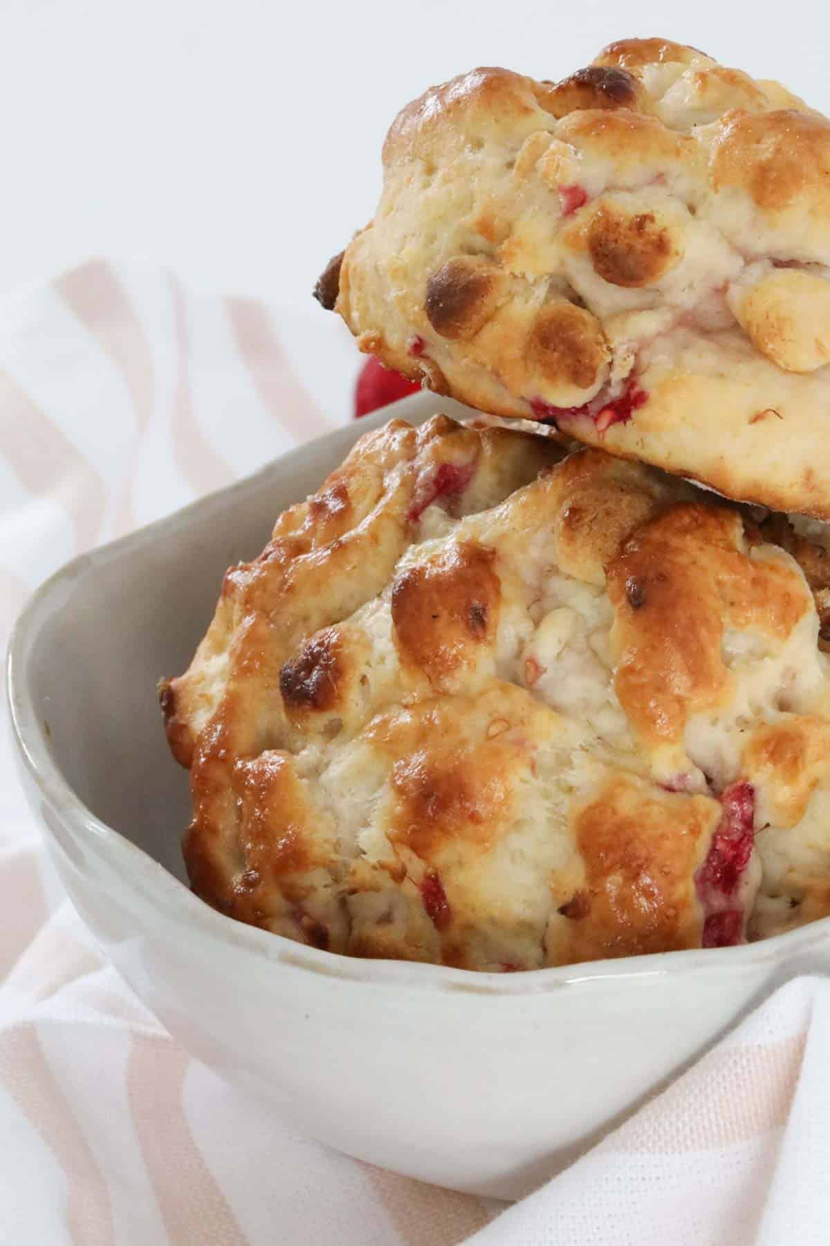 Two baked scones stacked in a bowl.