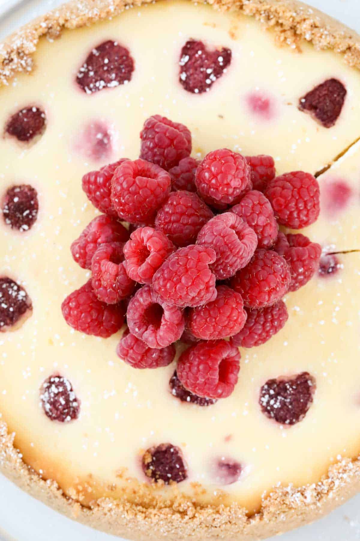 A pile of fresh raspberiies in the centre of baked cheesecake.