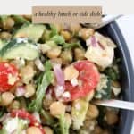 A large bowl of chickpea salad with avocado, tomatoes, feta and rocket.