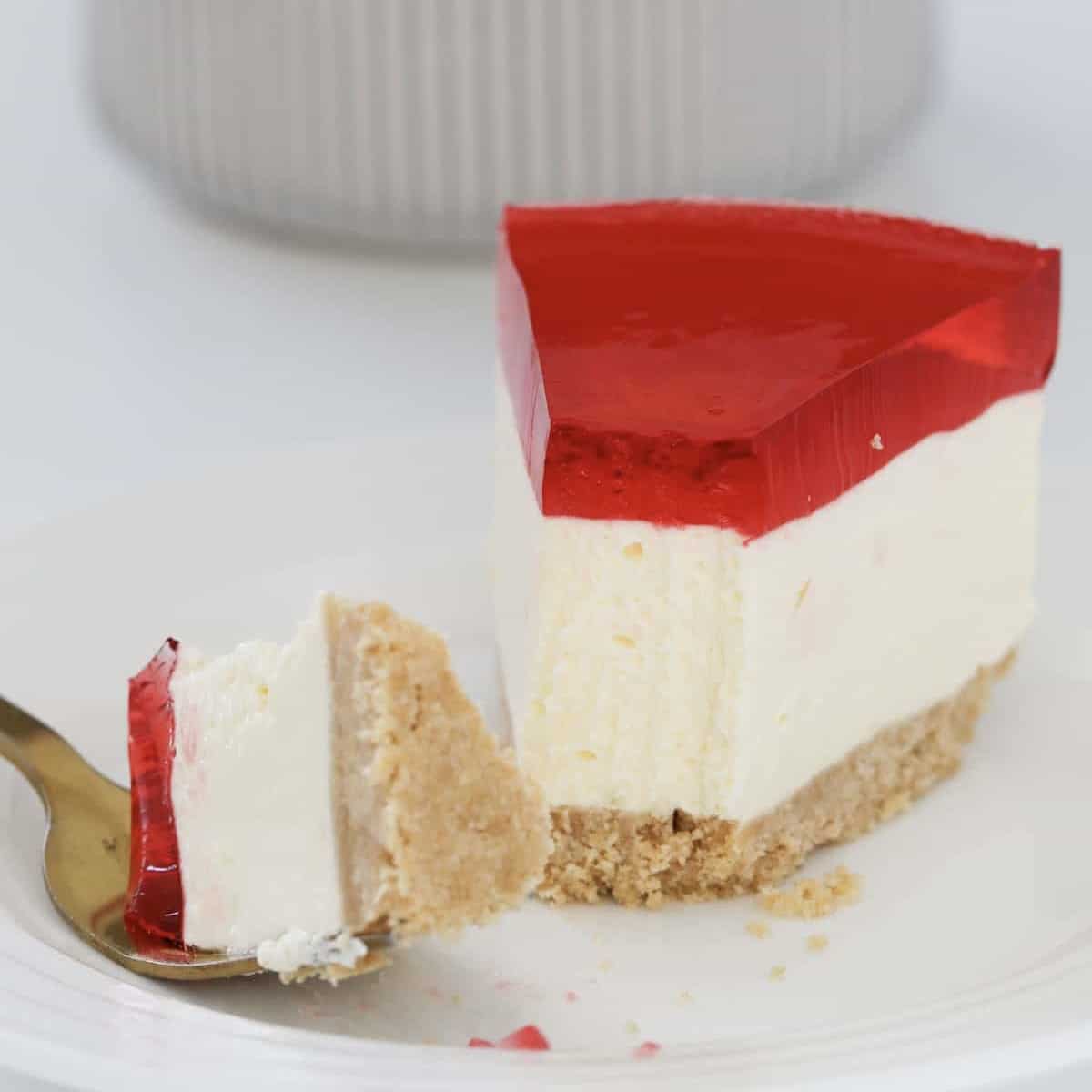 A piece of half eaten cheesecake topped with a jelly layer.