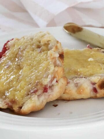 A halved scone with raspberries and white chocolate slathered in melted butter.