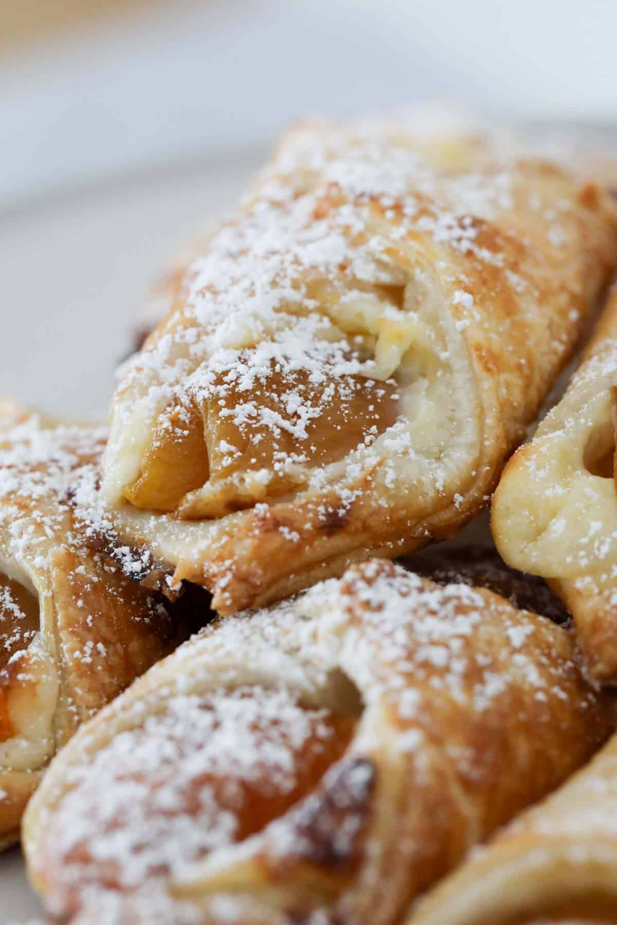 A close up of golden apricot danishes, lightly dusted with icing sugar.