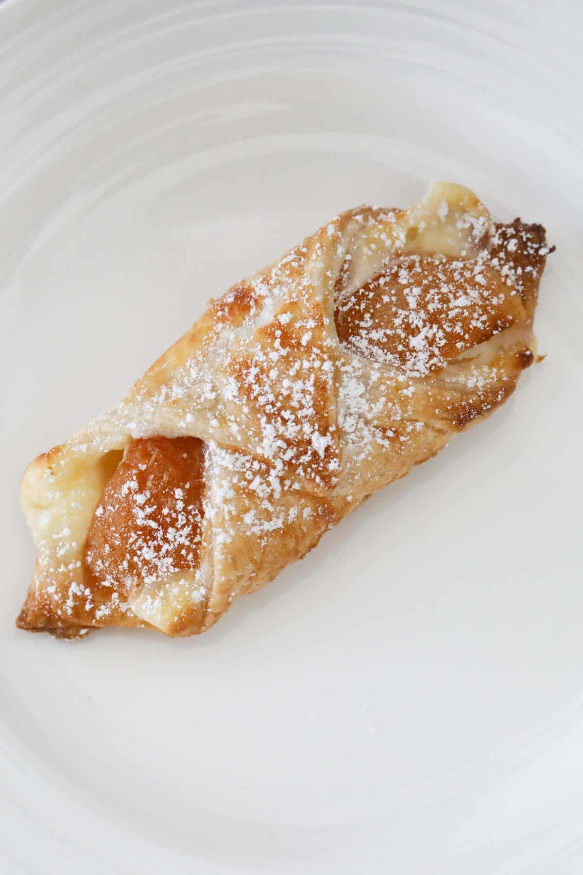 A golden baked danish dusted with icing sugar.