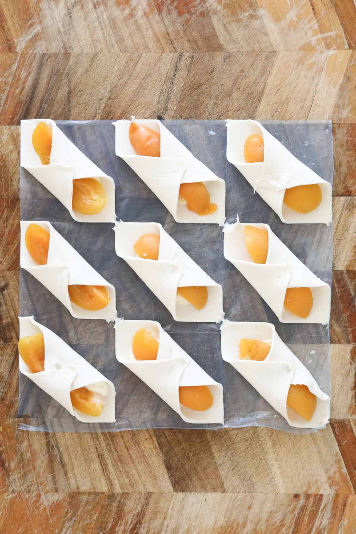 Opposite corners of pastry folded over apricot pieces and cream cheese mix.