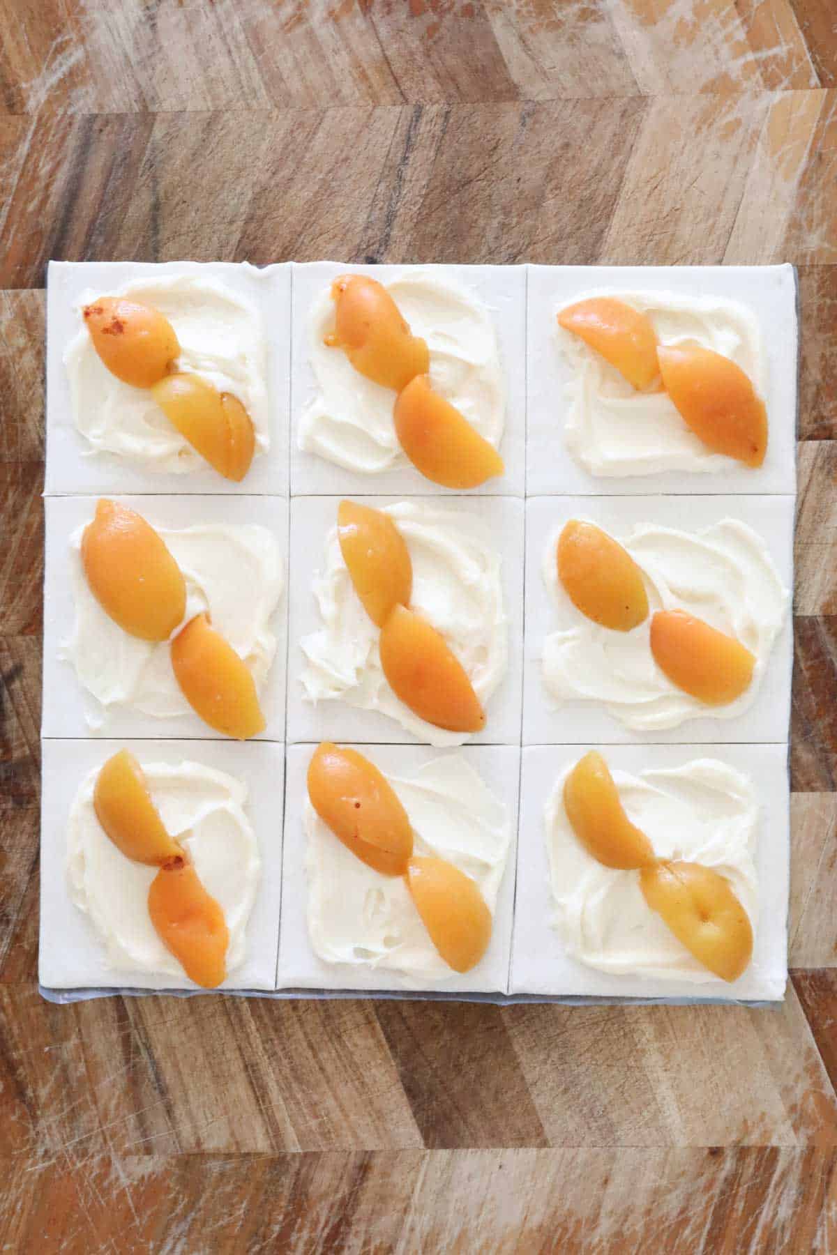 Two apricot quarters placed disgonally across cream cheese mixture on each pastry square.