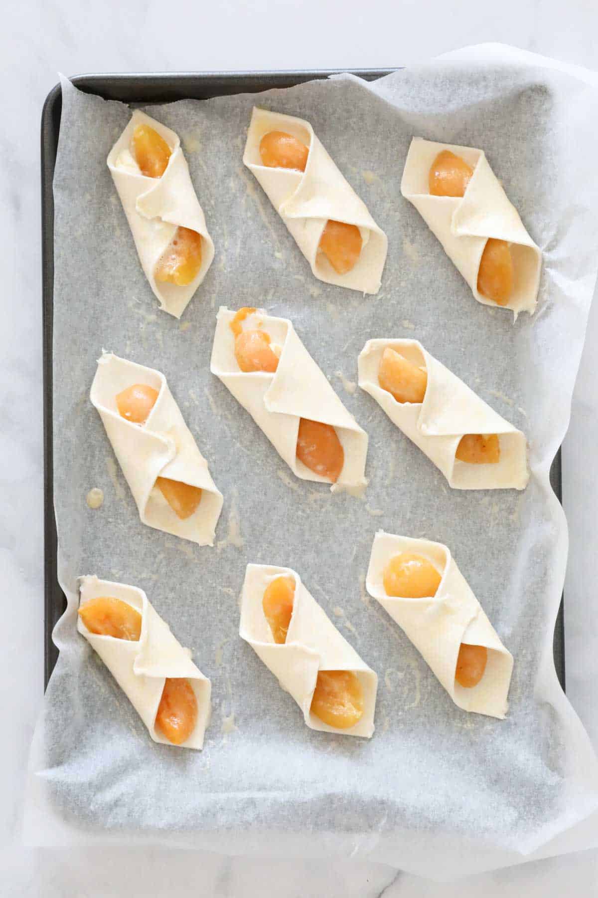 Unbaked danishes on a baking paper lined baking tray, ready to be chilled before baking.