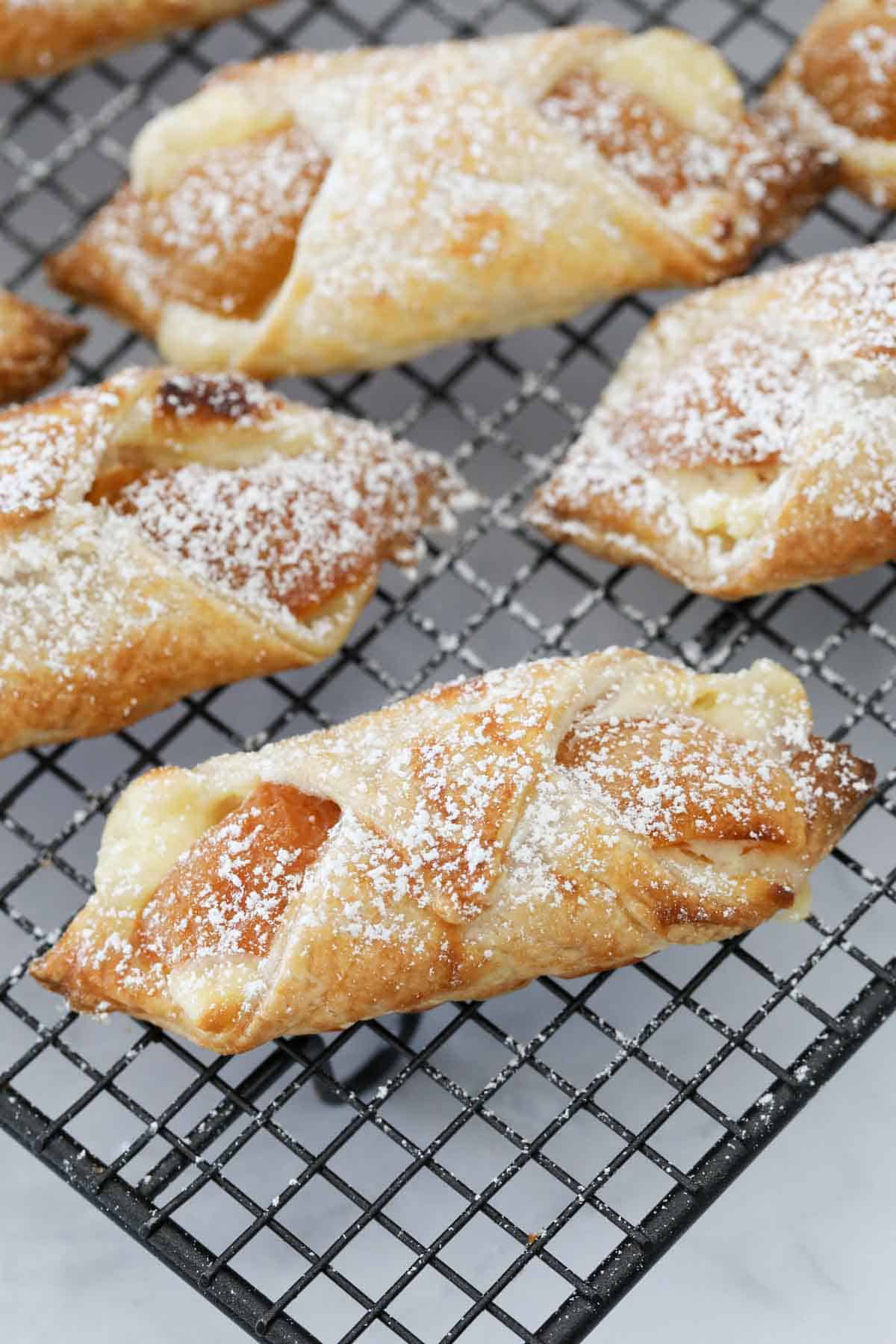 A close up of golden apricot danishes on a wire tray.