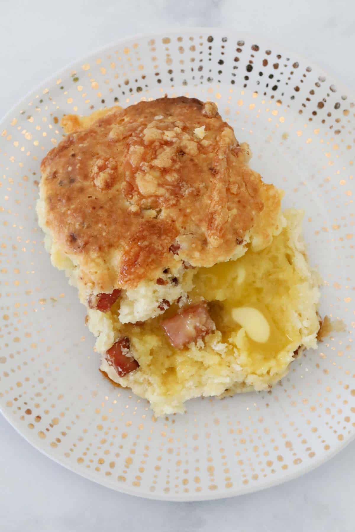 A bacon and cheese scone served with butter melted into it.