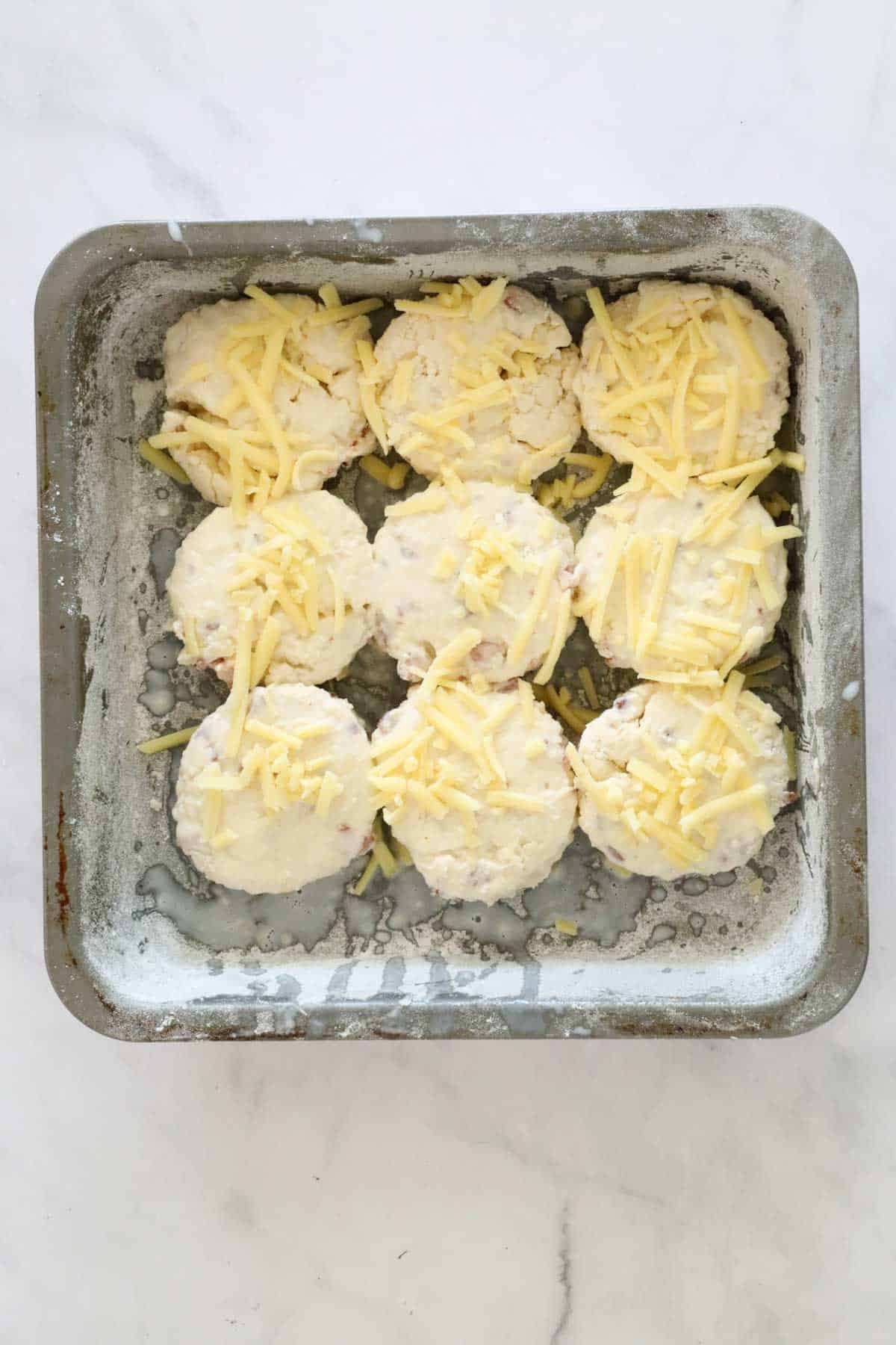 Cut out scone dough in the floured tin and sprinkled with grated cheese.