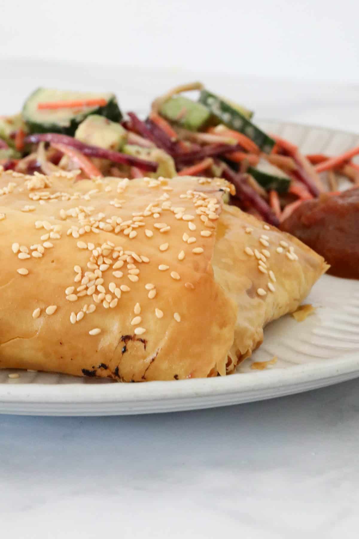 A chicken filo parcel on a plate served with salad.