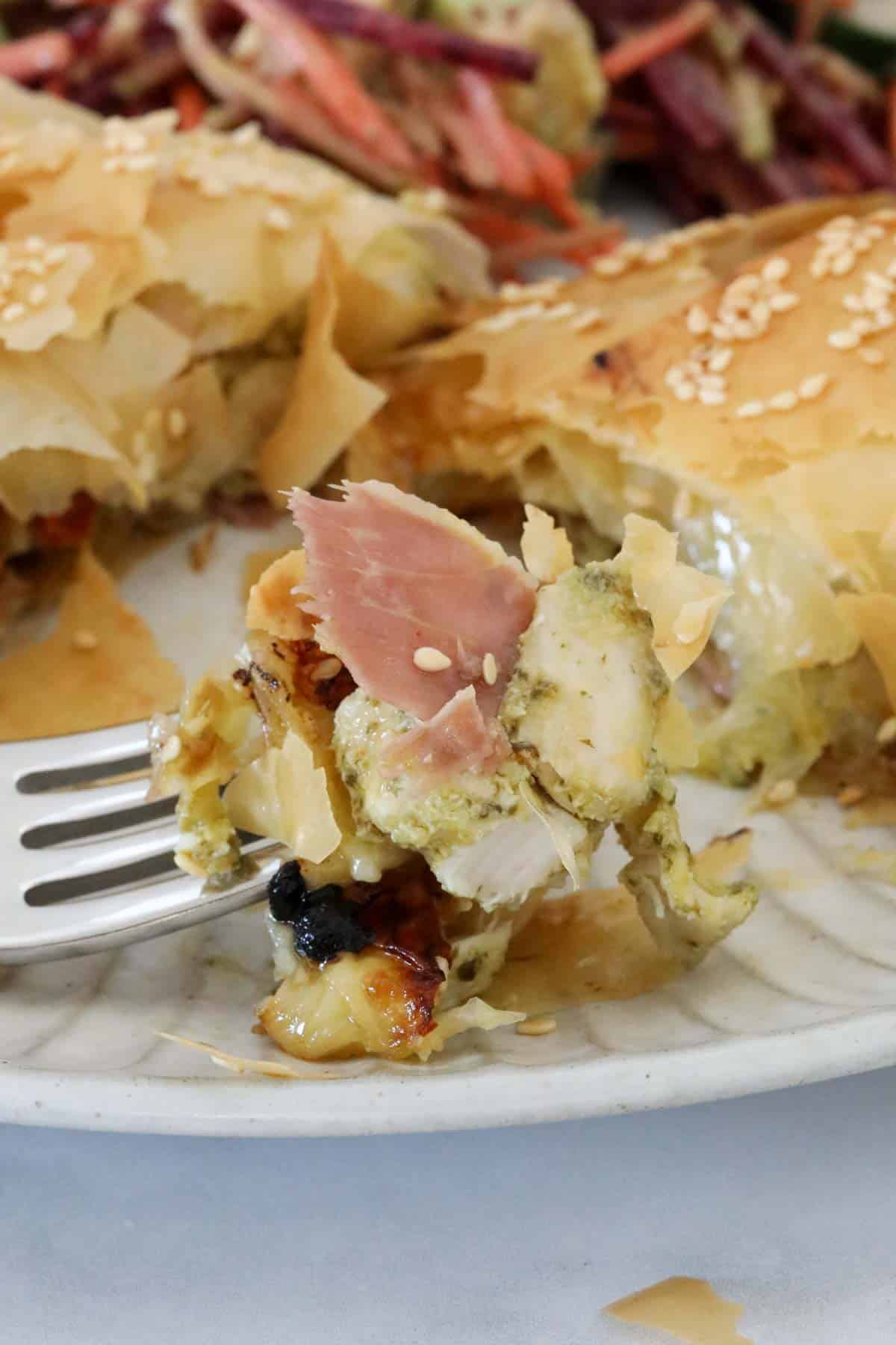 A fork holding up a mouthful of the chicken and prosciutto parcel.