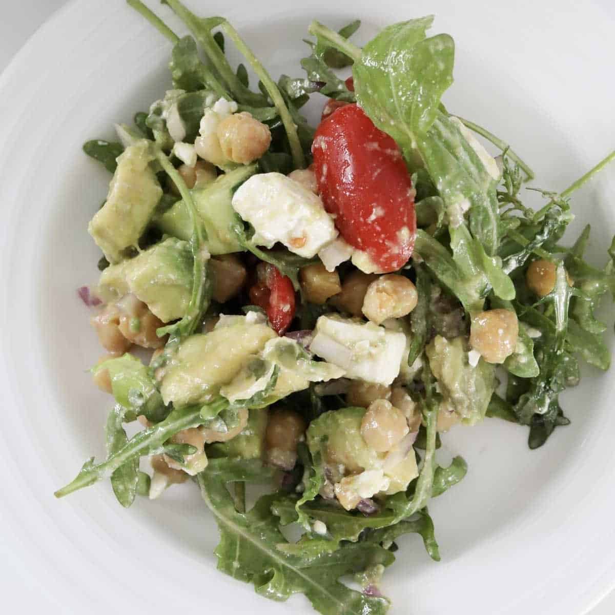 An overhead shot of a rocket, tomato, feta, chickpea and avocado salad.