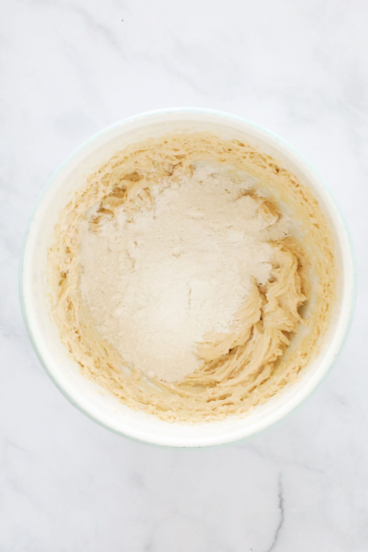 Sifted flour and baking powder over creamed mix in a bowl.