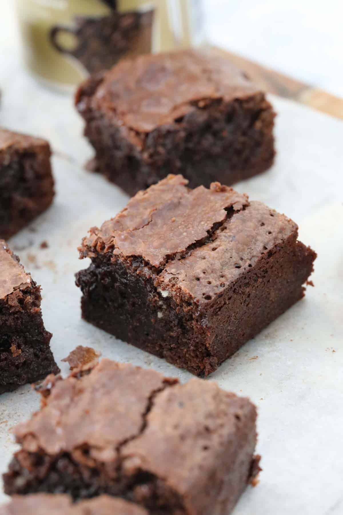 Squares of a fudgy brownie, placed on baking paper.