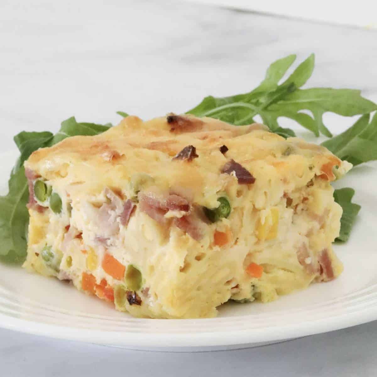 A slice of frittata with vegetables and macaroni.