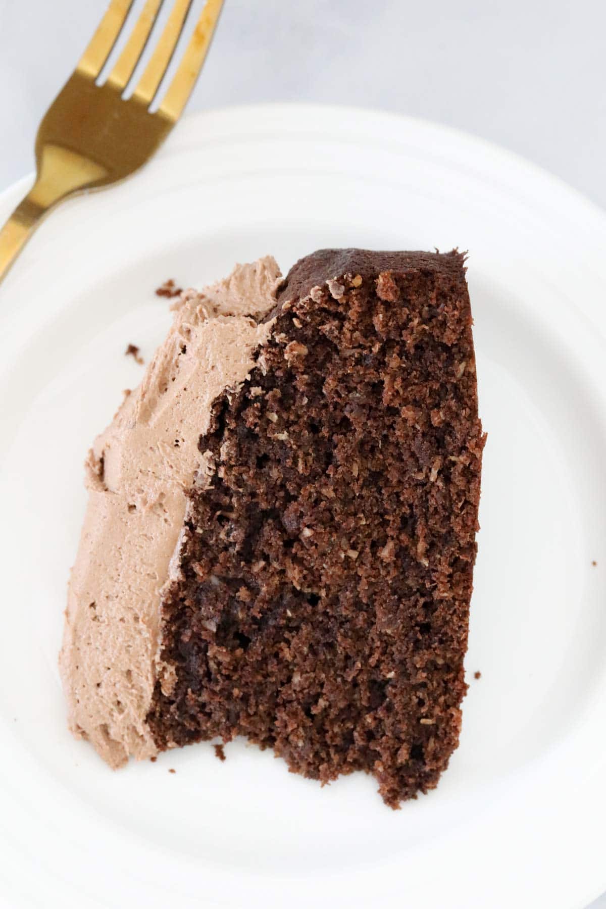 Close up of a slice of chocolate cake on a white plate.