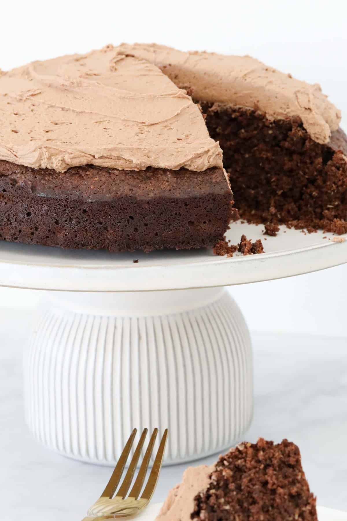 Melt and mix chocolate cake covered with chocolate buttercream, on a white cake stand.