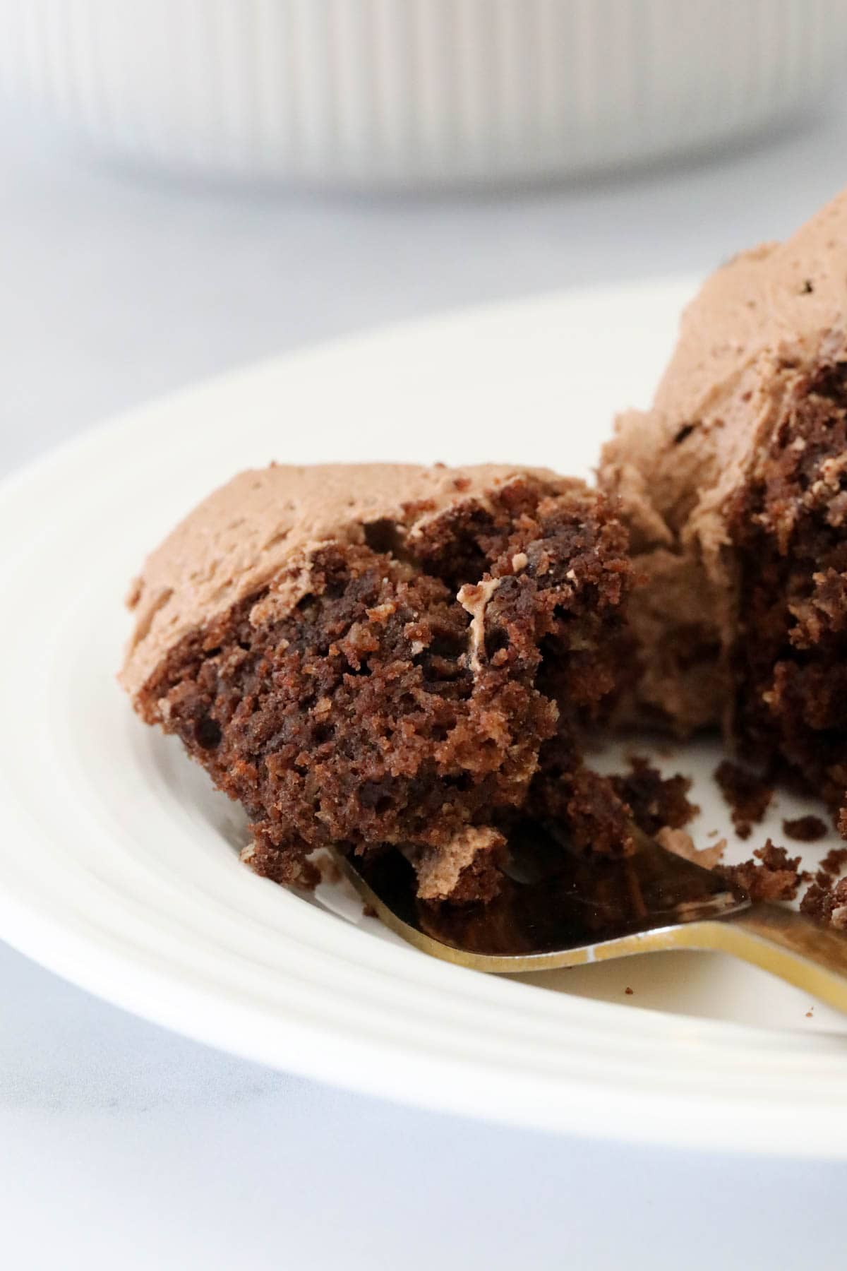 Close up of a forkful of cake on a white plate.