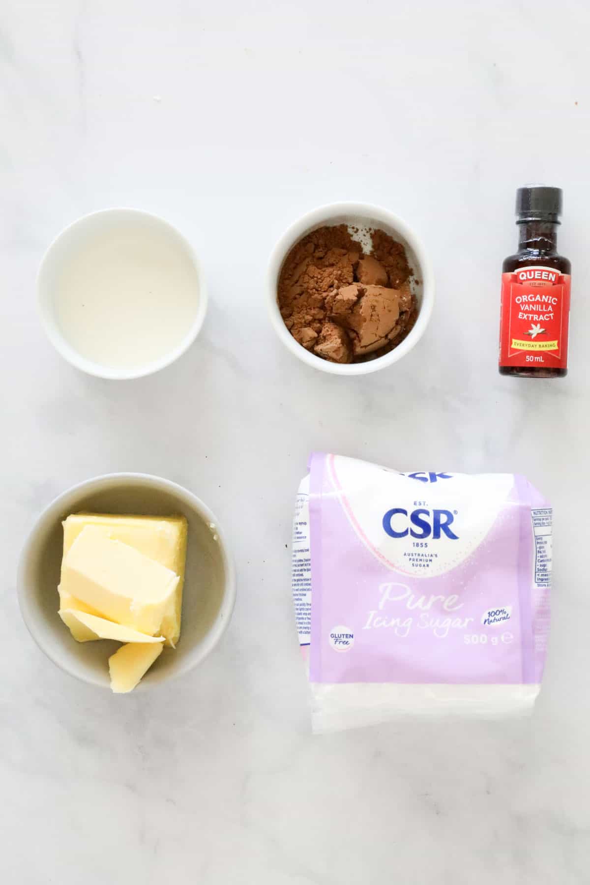 The ingredients needed to make chocolate buttercream weighed out and placed in individual bowls.