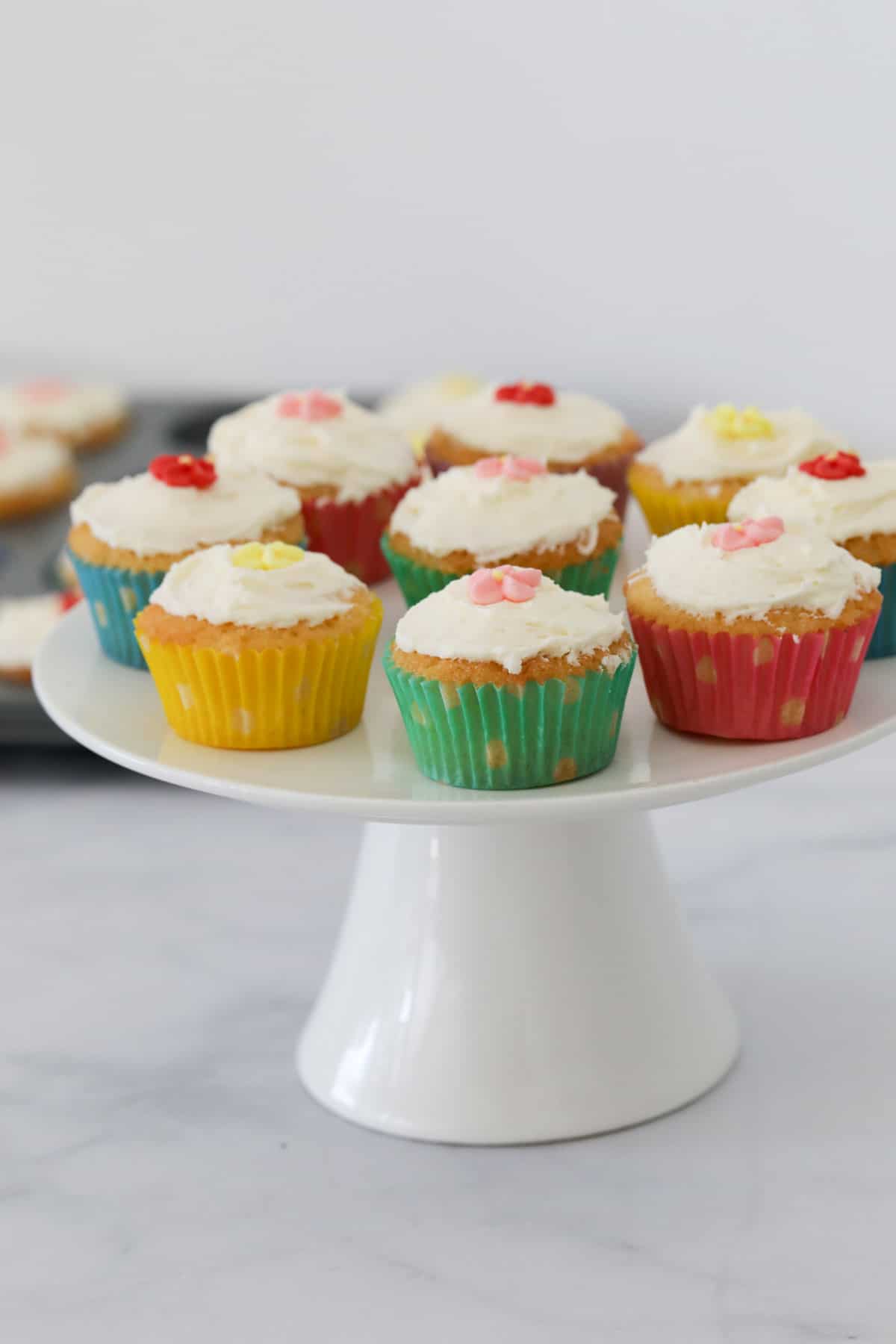 Frosted mini cupcakes on a white cake platter.