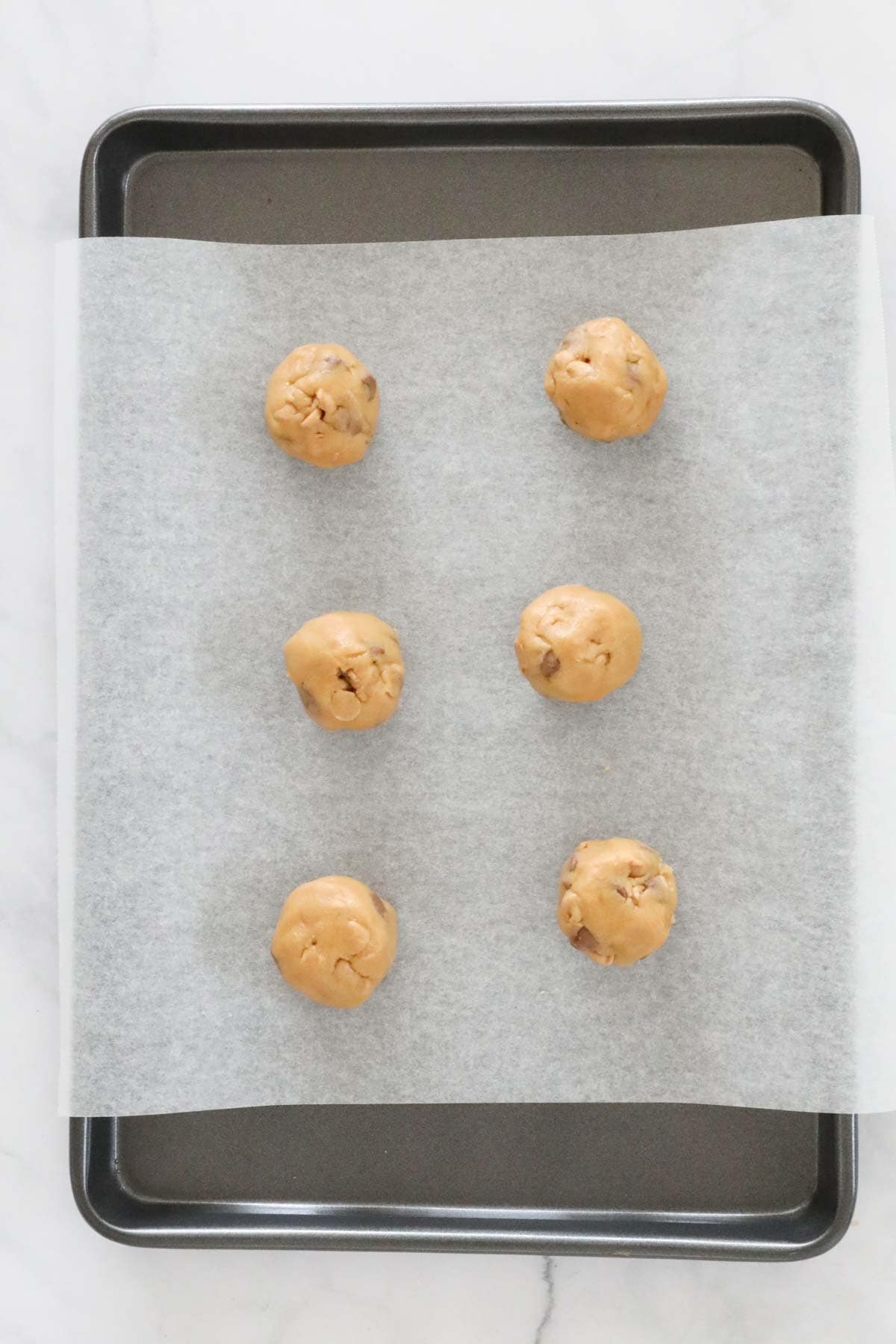 Cookie dough rolled in to balls and placed on a lined baking tray.