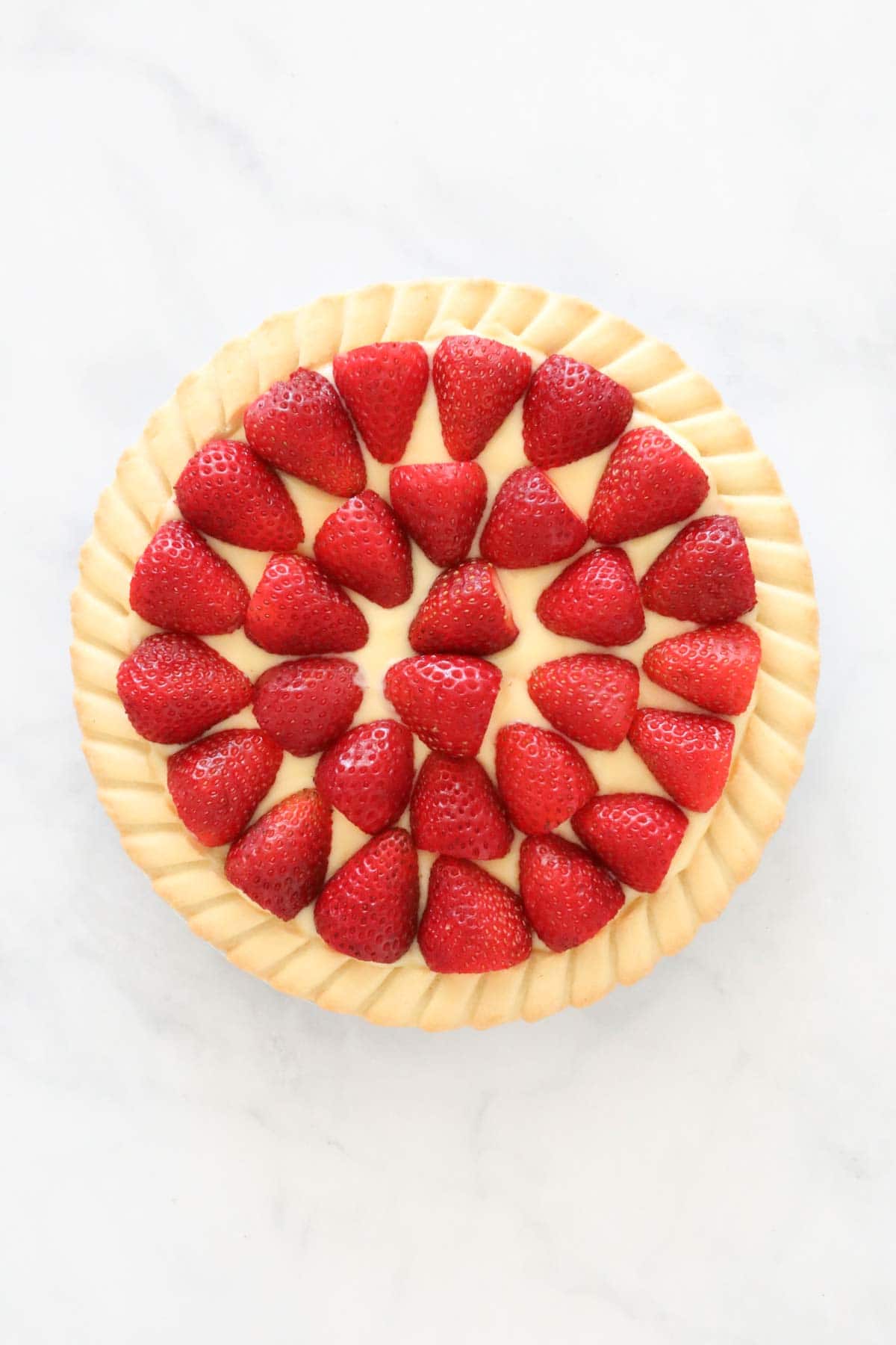 Strawberry halves arranged on top of the custard in the pastry case.