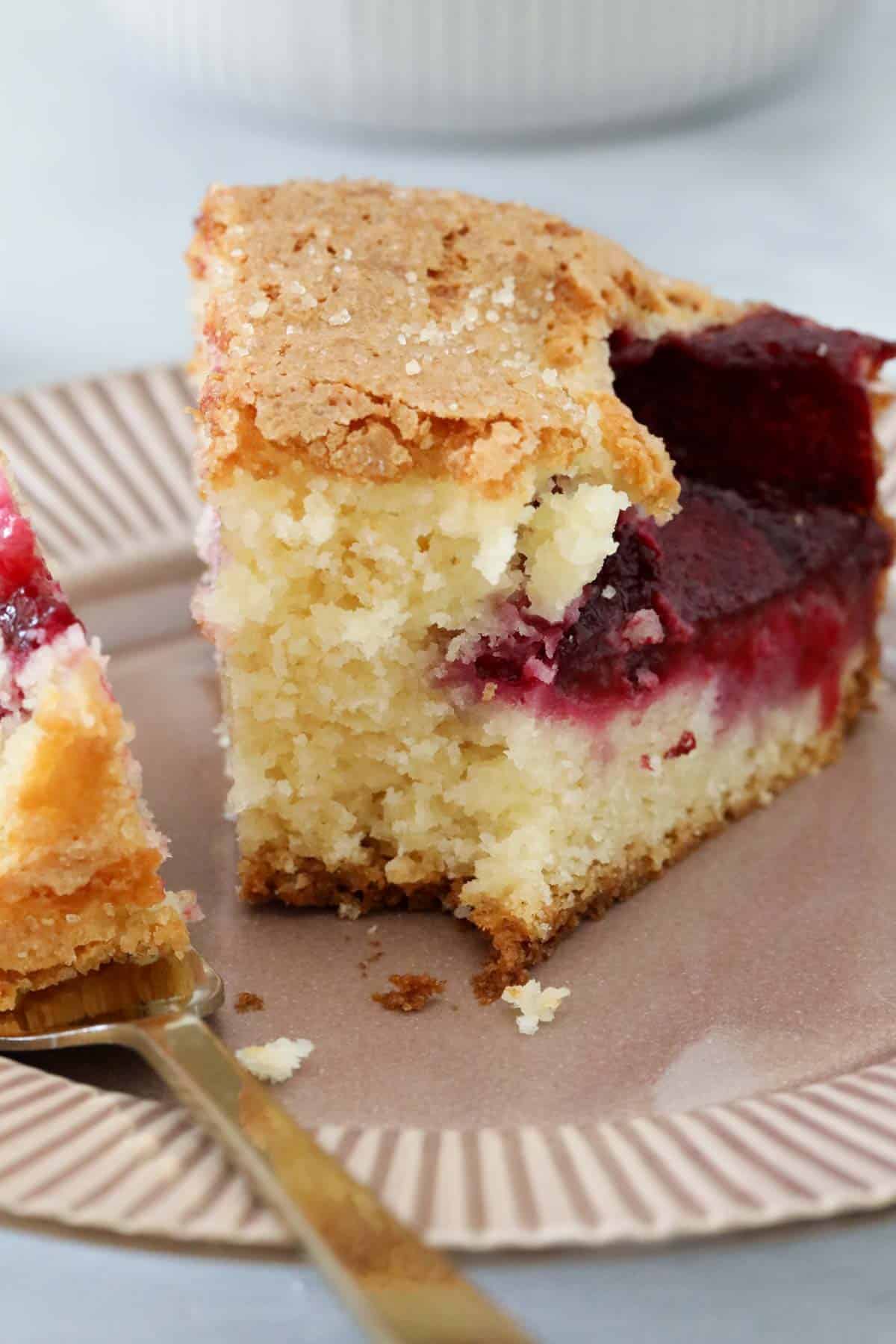 A slice of plum cake on a plate with a fork holding a small portion of the cake.