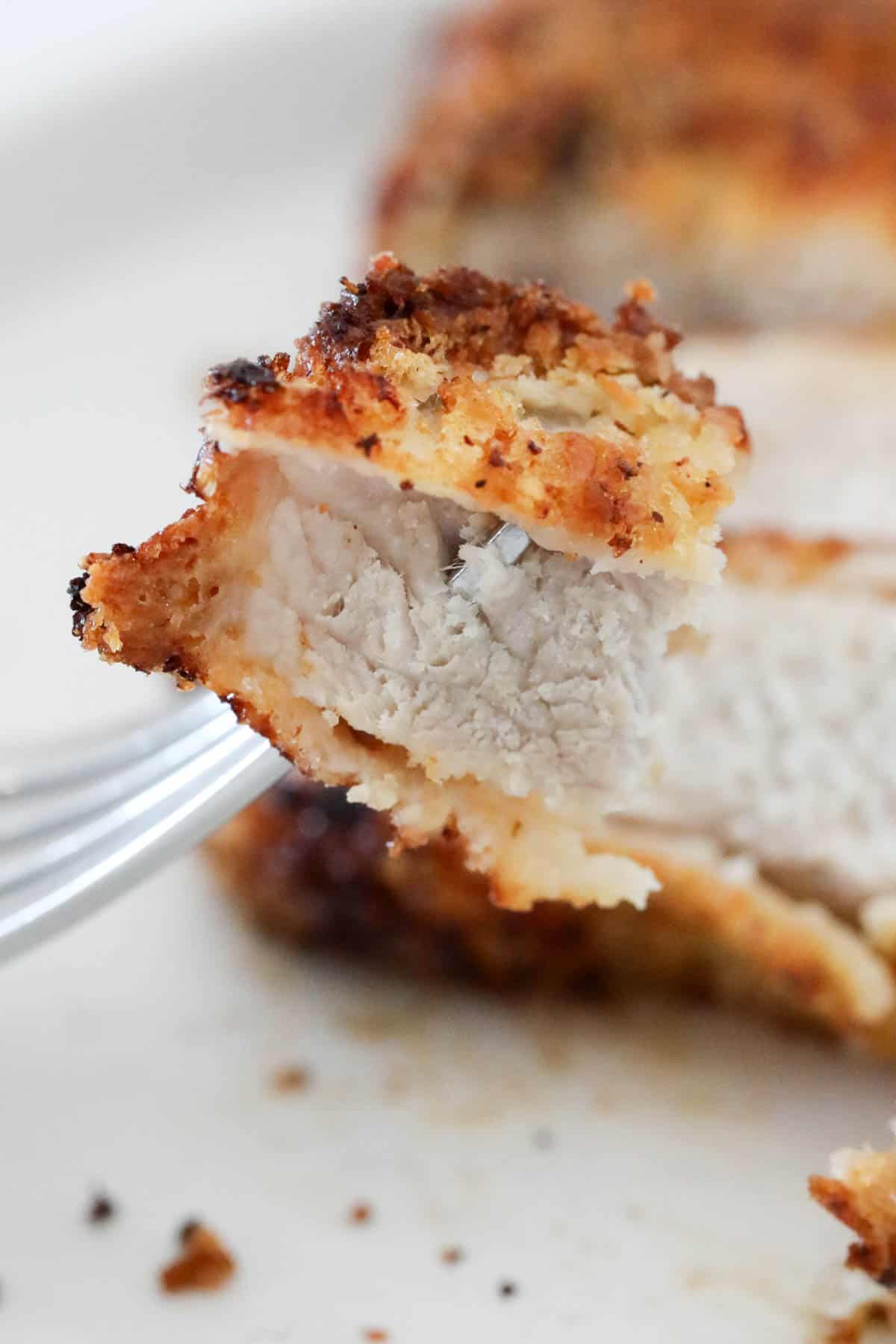 Mouthful of air fryer pork chop on a fork.