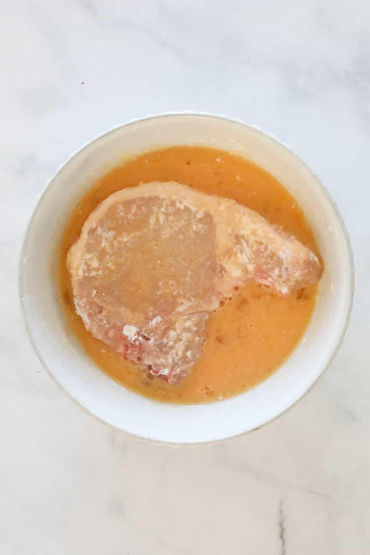 A pork chop dipped into beaten egg.