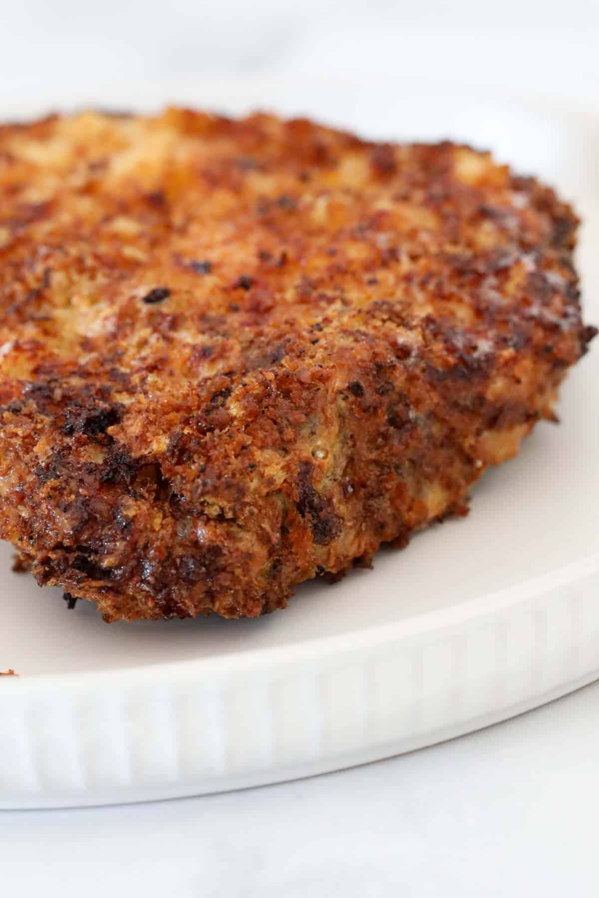 Close up of the crispy crumbed pork chop on a plate.