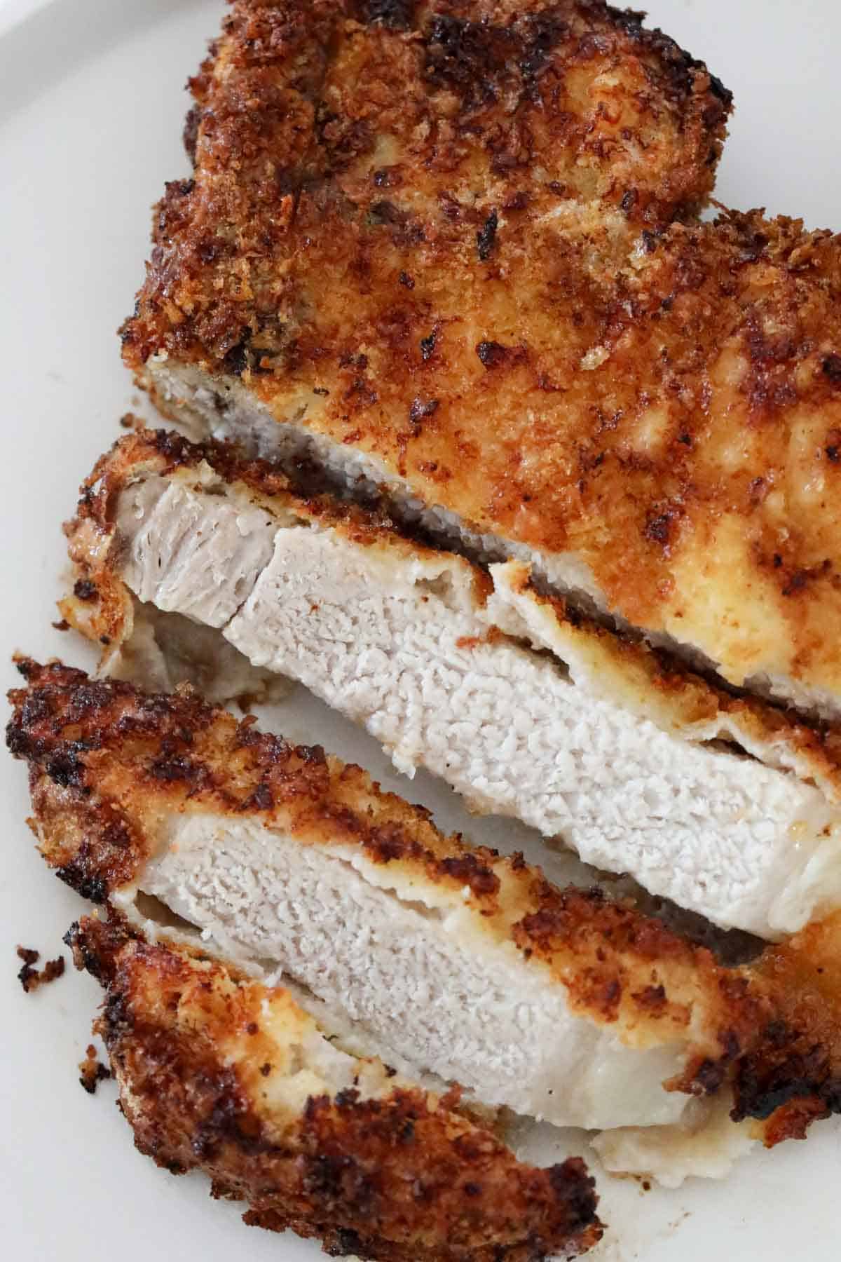 An air fryer breaded pork chop cut to show the juicy cooked pork centre.