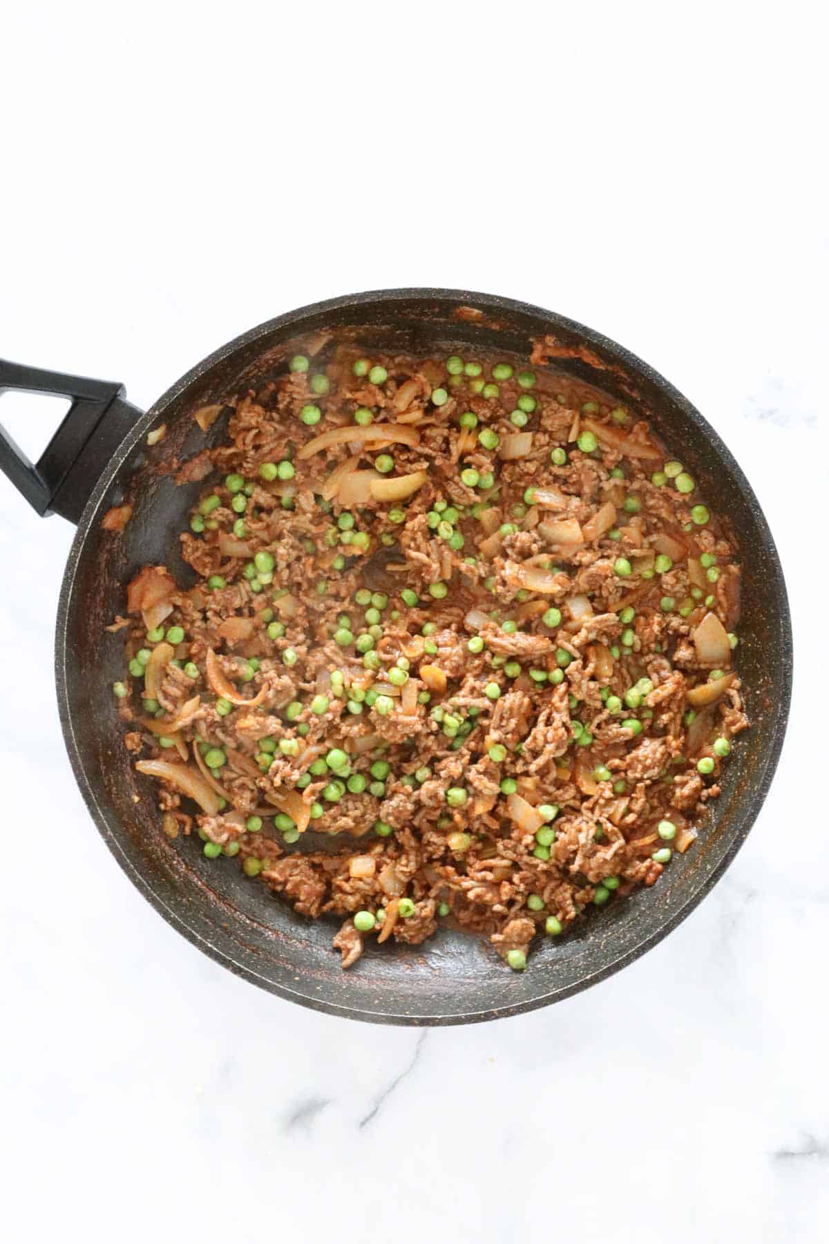 Frozen peas added to the beef mixture.