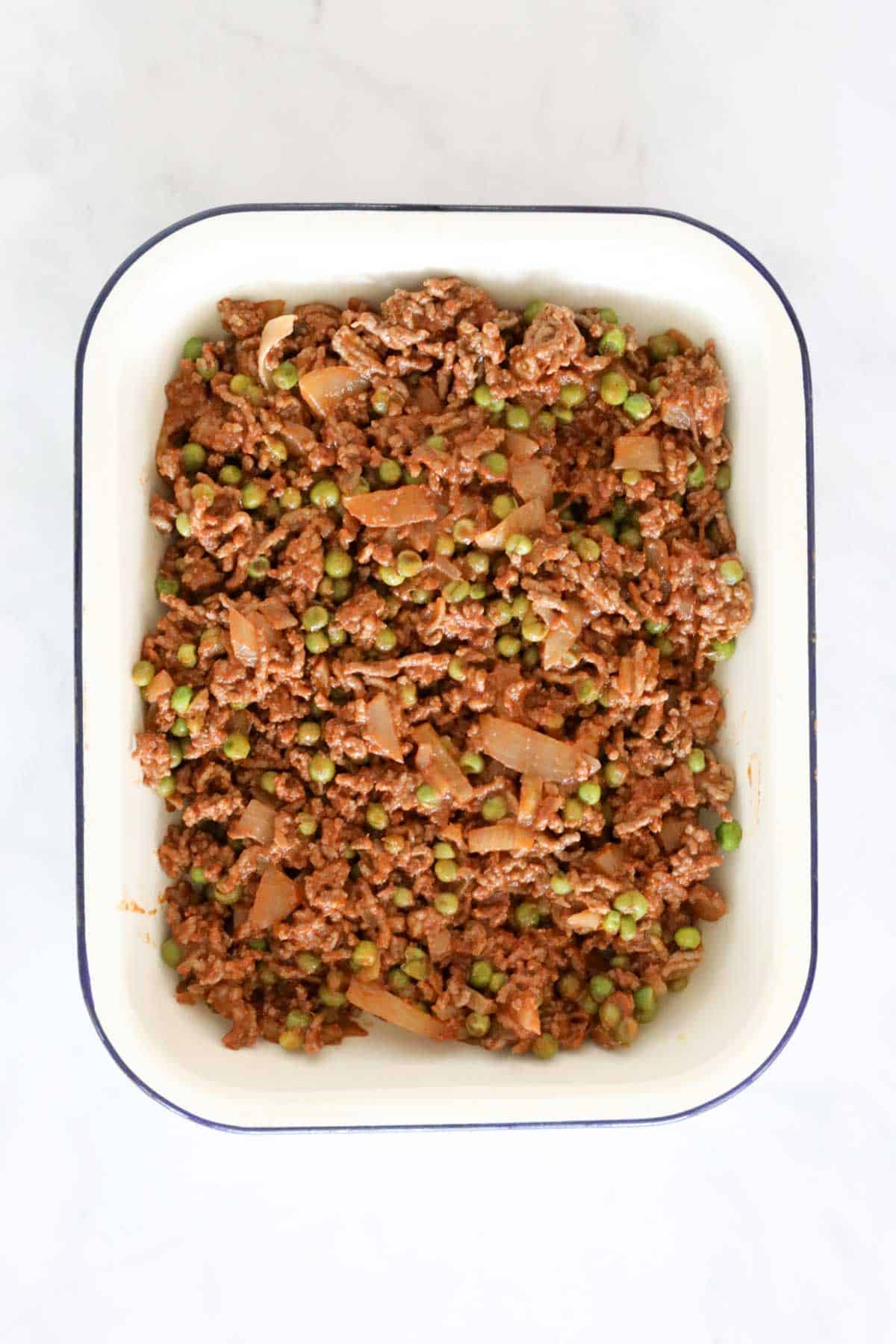 The beef mixture in the bottom of a pie dish.