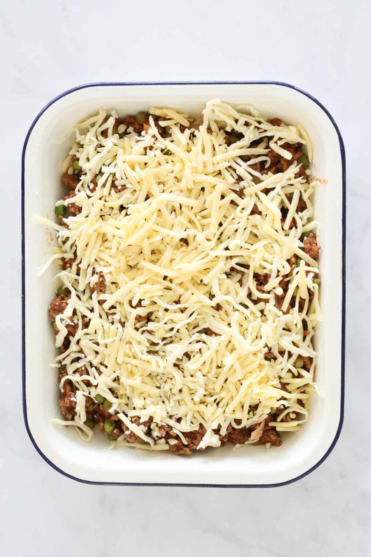 Grated cheese sprinkled over the beef mince in the baking dish.