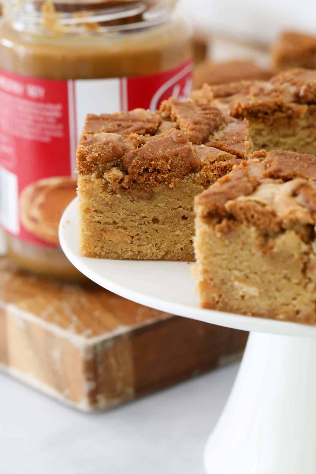 A close up of squares of blondie served on a white cake stand.